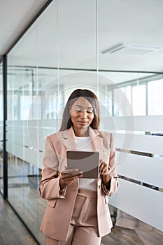 Young professional business woman using tablet standing in office, vertical.