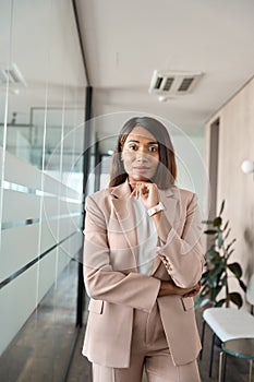 Young professional business woman wearing suit standing in office, portrait.