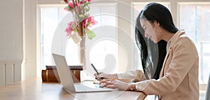Young professional businesswoman working on her project while typing on laptop computer in comfortable room