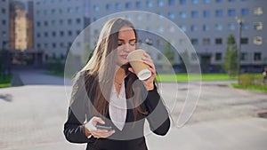 Young professional caucasian businesswoman or female student, woman walking and using mobile phone, smartphone, texting