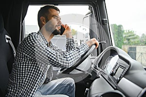 Young professional driver communicating over mobile phone while driving a truck