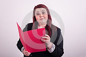 Young professional female holding an open a red file folder pointing at it