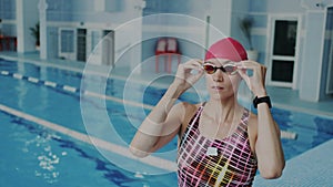 Young professional female swimmer putting on her goggles on her face for underwater floating, She wear swimsuit and red