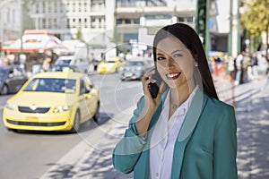 A young, professional, Greek woman in corporate outfit stands in the city center of Athens
