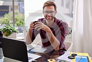 Young professional holding coffee and smiling at his desk photo