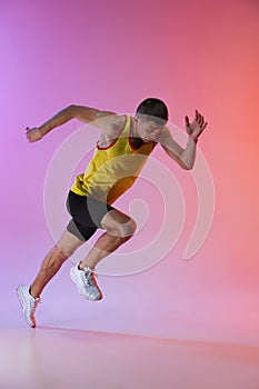 Young professional male athlete isolated over gradient studio background. Running photo