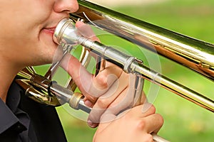 young professional musician in black shirt teaching correct trombone mouthpiece playing position