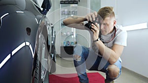 A young professional photographer a guy, a man takes pictures of a car in a car salon. Concept: lifestyle, new photo, car, photo