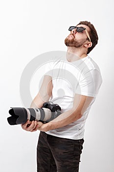 Young professional photographer in shirt holds heavy digital cam