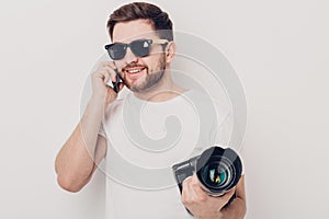Young professional photographer in white shirt holds digital cam