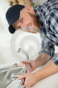 young professional plumber assembling sink pipe