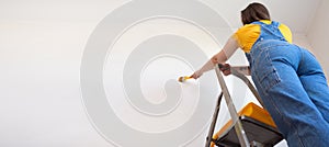 Young Professional repair woman with priming or painting the wall with brush. Independent single female makes repairs