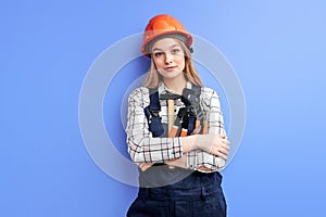 Young professional service woman wearing orange helmet and blue coverall holding wrench, hammer and other tools