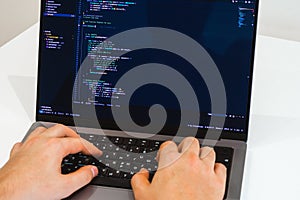Young professional software engineer, IT specialist, programmer, working at home and writing code on a laptop computer.