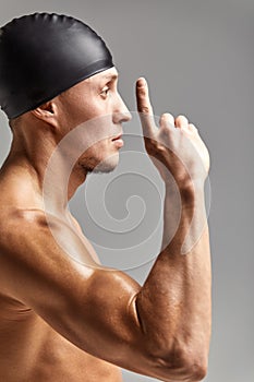Young professional swimmer man indicates with fingers up showing a blank space.