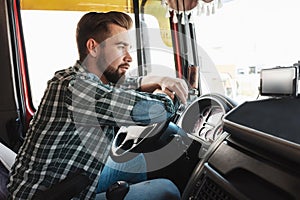 Young professional truck driver sitting inside his vehicle