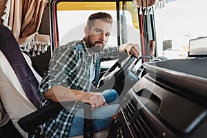 Young professional truck driver sitting inside his vehicle