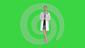 Young professional woman doctor wear uniform with stethoscope talking to camera on a Green Screen, Chroma Key.