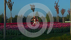 Young professional woman playing contrabass in blooming summer garden outdoor.