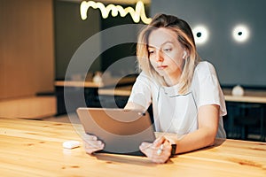 Young professional woman sitting in modern coworking space uses digital tablet.