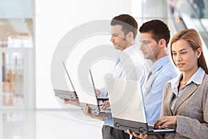 Young professionals using laptop in office lobby