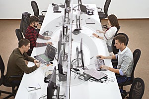 Young professionals working in modern office. Group of developers or programmers sitting at desks focused on computers photo