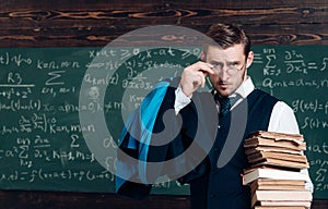 Young professor holding pile of books looking over his glasses. Aristocrat scholar in elite college