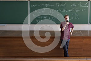 Young professor lecturer with microphone speaking and teaching students in large lecture hall