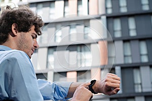 Young progressive businessman using touchscreen smartwatch to check time.