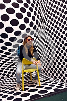 Young protagonist posing on yellow chair and black and white psychedelic background