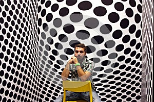 Young protagonist posing on yellow chair and black and white psychedelic background