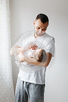 Young proud Caucasian father playing with newborn baby. Man parent holding rocking child daughter son on hands. Authentic