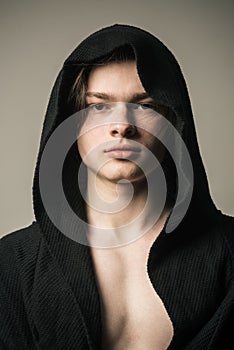 Young pugilist in black hood isolated on gray background. Handsome fighter before going to boxing ring. Muscular guy photo