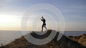 Young pugilist male practicing boxing blows before sparring on hill near river