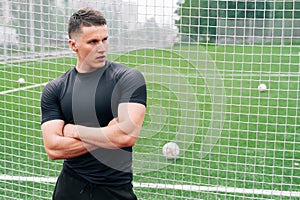 A young pumped man in sportswear stands against the background of the football gate. The concept of football coach