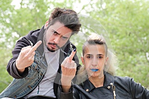 Young punk couple flipping the bird to the camera in a park