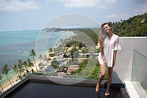 The young quite stylish sensual woman posing on the amazing tropical beach with the blue ocean enjoy her holiday and a windy summe