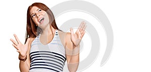 Young read head woman wearing casual clothes crazy and mad shouting and yelling with aggressive expression and arms raised