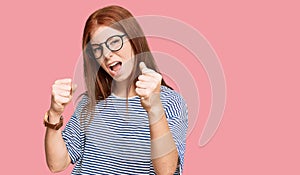 Young read head woman wearing casual clothes and glasses angry and mad raising fists frustrated and furious while shouting with