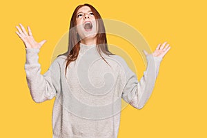 Young read head woman wearing casual winter sweater crazy and mad shouting and yelling with aggressive expression and arms raised