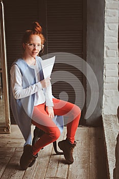Young hipster student woman or creative freelance designer working on project. Holding coursework or business plan. photo