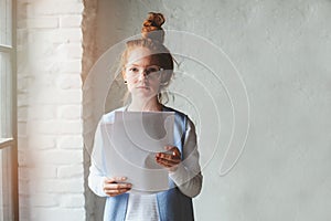 Young hipster student woman or creative freelance designer working on project. Holding coursework or business plan. photo