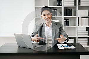 Young real estate agent worker working with laptop and tablet at table in modern office and small house beside it