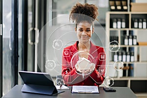 Young real estate agent worker working with laptop and tablet at table in office and small house beside it