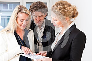 Young realtor explaining ground plan to couple