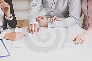 Young realtor showing contract with floor layout in an apartment to a young couple