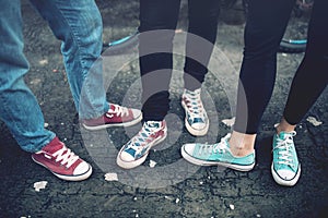 Young rebel teenagers wearing casual sneakers, walking on dirty concrete. Canvas shoes and sneakers on female adults