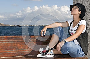 Young rebel woman sitting near the sea