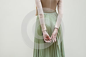 Young red hair girl in hat, dressed in beige blouse and turqoise pleats skirt, on light street backgraund.