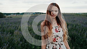 A young red-haired girl happily walking in slow motion through green field. Joy, beauty in nature and environment